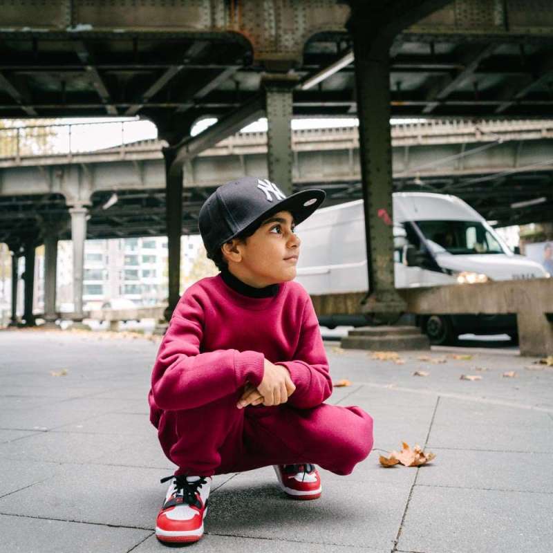 Children Urban Basic Jogginghose - Bordeaux Kind unter der Brücke sitzend