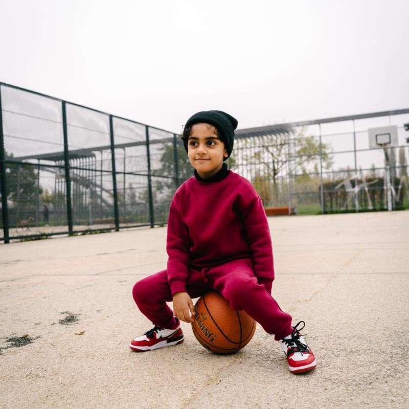 Children Urban Basic Jogginghose - Bordeaux Kind auf Basketball sitzend